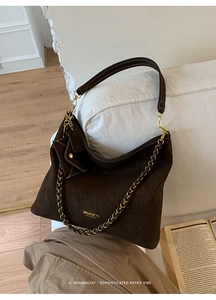 Detail of dark brown suede hobo bag with gold chain and mini coin purse pendant