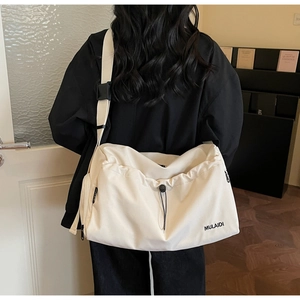 Detail of a cream canvas travel bag with adjustable strap shown in a home setting