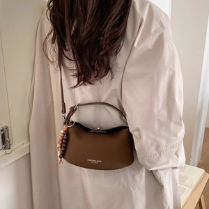 Detail of dark brown leather hobo bag with wooden bead pendant and fashion lettering
