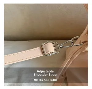 Detail of light pink canvas bag showing adjustable faux leather strap and silver buckle
