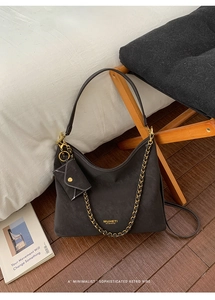 Detail of black matte tote with gold chain strap and mini envelope pouch accessory