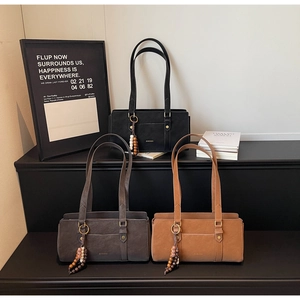 Detailed view of matte shoulder bags in black, gray and tan with decorative wooden beads