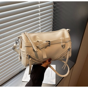 Detailed view of cream PU leather shoulder bag with tassels and silver buckles