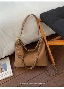 Detail of brown matte leather tote bag with gold chain and matching card pouch hanging