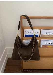 Detail of dark brown suede hobo bag with gold chain strap and mini pouch charm