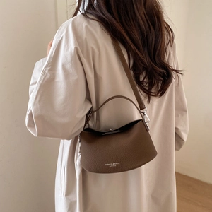 Detail of dark brown lychee grain leather handbag with silver buckle and shoulder strap