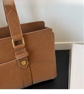 Detail of high-quality golden metal buckle and stitching on vintage brown leather handbag