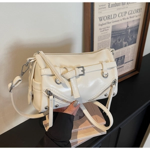 Detail view of cream white motorcycle bag with silver metal buckles and retro newspaper