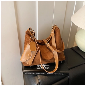 Close-up of a brown suede hobo bag with a small coin purse on a designer book