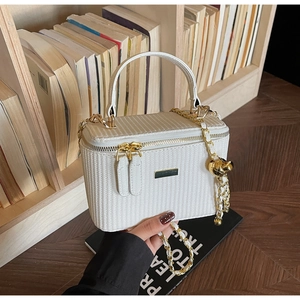 Close-up of woven texture white box bag with gold chain strap and metal clasp detail