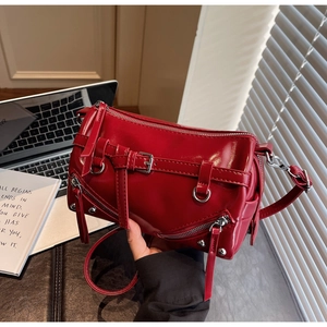 Detail of glossy red faux leather shoulder bag with metallic zippers and buckle accents
