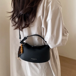 Detail of black lychee grain leather dumpling bag with decorative wooden beads charm