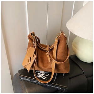 Detail of a brown suede tote bag with leather handles and a matching coin purse on a book