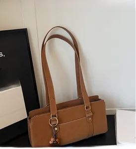 Close-up of brown retro Boston handbag with metal ring charm and woven detail
