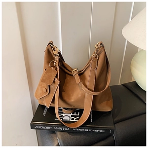 Detailed macro view of brown suede tote bag with white stitching and gold hardware accents