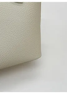 Détail du sac seau crème montrant le cuir grainé lychee et les coutures de précision