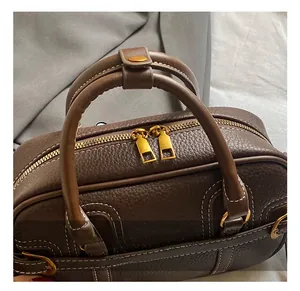 Detail view of premium gold hardware double zippers and white contrast stitching on leather bag