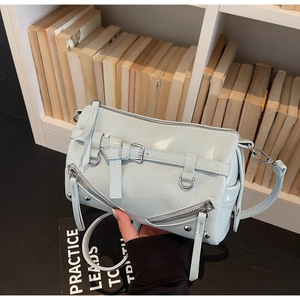 Detailed view of silver hardware and studs on a glossy light blue motorcycle crossbody bag