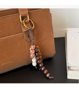 Detailed close-up of a retro ethnic style wooden beaded charm on a leather handbag