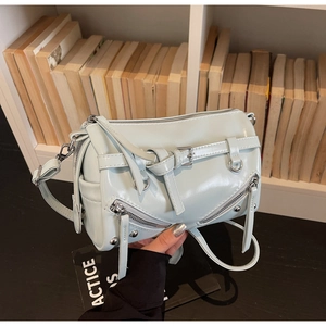 Detailed shot of mint blue faux leather cylinder bag with silver buckles and punk studs