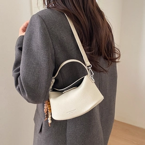 Detailed view of white lychee leather texture on a retro crossbody dumpling bag