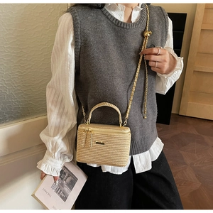 Detail of beige woven straw box bag with golden chain strap and metallic clasp