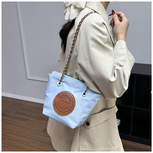 Détail du sac seau en nylon bleu clair avec écusson chiot et bandoulière en chaîne métal