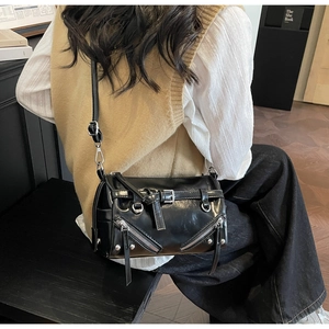 Detail of black motorcycle crossbody bag with silver rivets and zippers on glossy leather
