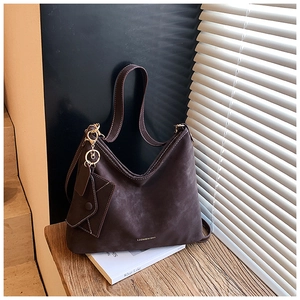Detail of dark brown suede tote bag with metal logo and matching envelope pouch