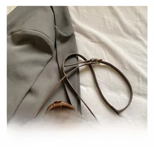 Detail of adjustable leather shoulder strap and brass hardware on vintage brown square bag