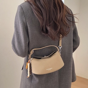 Detail view of khaki crescent bag with litchi texture leather and wooden bead charm