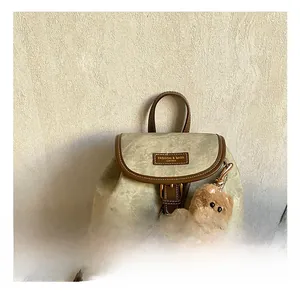 Detail of vintage canvas and leather backpack featuring front buckle and cute dog charm