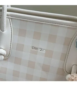 Close-up of beige plaid pattern fabric and logo on a stylish large capacity tote bag