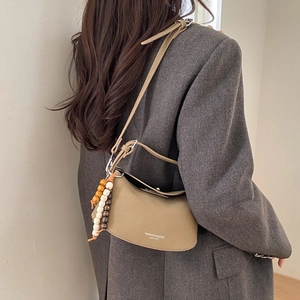 Detail of khaki leather crossbody bag with beaded charm and fashion lettering