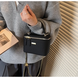 Detail of black woven texture small box bag with gold double zippers and chain strap