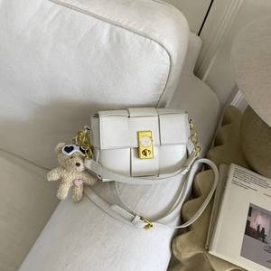 Détail du sac à bandoulière tressé crème avec fermoir horloge doré et breloque ours