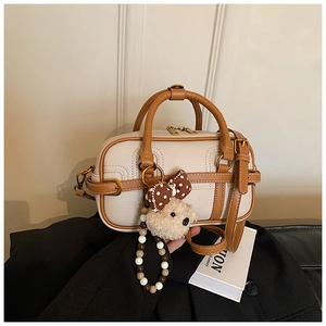 Detail of cream pebbled leather bowling bag with brown trim and cute bear charm