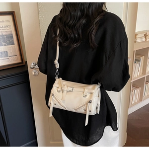 Close-up of retro cream shoulder bag featuring silver zippers and punk motorcycle style