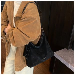 Close-up of black matte suede shoulder bag with gold logo and detachable mini pouch
