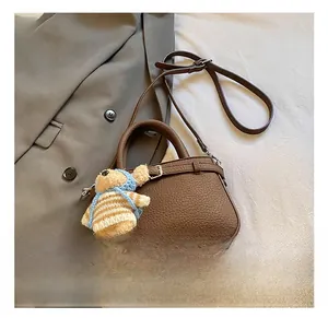 Brown lychee leather bucket bag with adjustable strap and cute teddy bear charm
