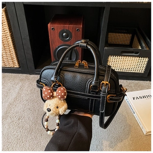 Detail of black lychee grain mini bag with contrast stitching and cute puppy charm