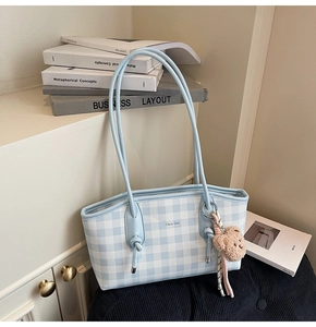 Détail du sac cabas à carreaux bleu clair avec de longues anses et un petit ours en peluche