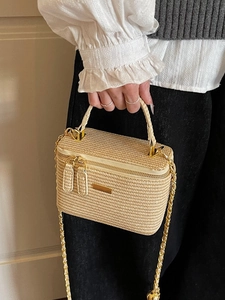 Beige woven vanity bag with top handle and gold chain strap shown on a model