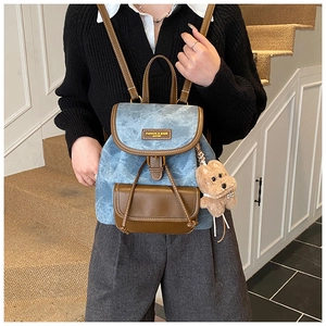 Detail of vintage denim canvas backpack with leather flap and cute bear pendant