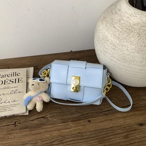 Détail du sac en cuir tressé bleu clair avec fermoir doré et charm ours mignon