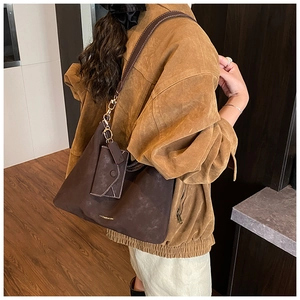 Detail of dark brown suede tote bag featuring white contrast stitching and gold logo