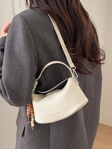 Off-white lychee grain leather dumpling bag with beaded charm on a blazer model