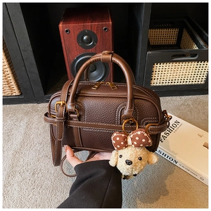 Detail of dark brown leather Boston bag with white stitching and puppy charm