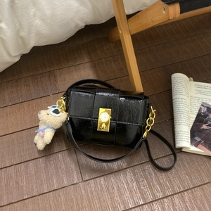 Détail du sac bandoulière tissé en cuir verni noir avec fermoir doré et breloque