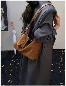 Detail of brown suede tote bag with golden hardware and matching envelope charm